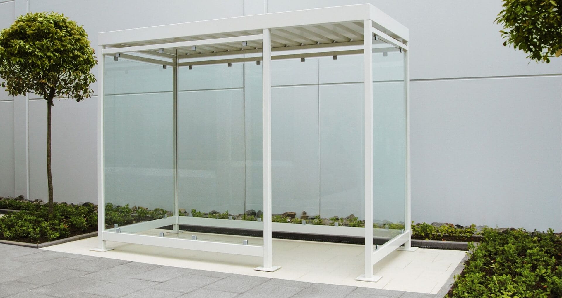 Witte rookhok van staal en glas in een strakke buitenruimte met beplanting